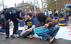 A U-M police officer talks with Kevin Mersol-Barg (BA '13) as he sits in the middle of State Street, blocking the flow of traffic.