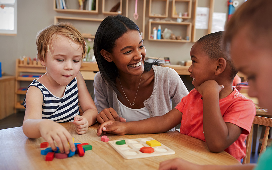 Photo of a teacher and three young elementary school students around a classroom table