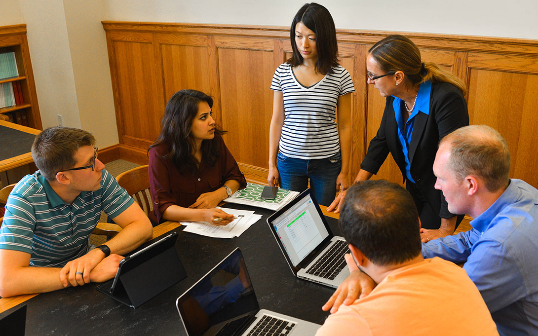 Photo of Professor Liz Gerber and a group of Ford School MPP students seated around a table, having a conversation