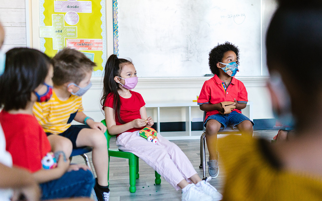 Photo of a young, diverse group of masked students in a classroom