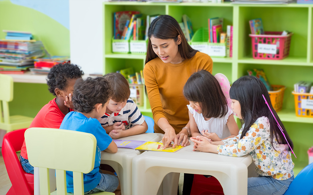 Kindergarten teacher with students at a table