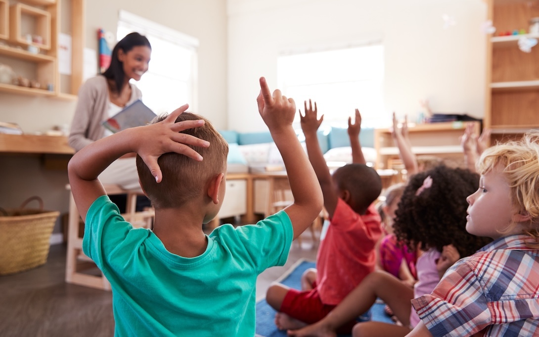 children raising their hands in a classroom