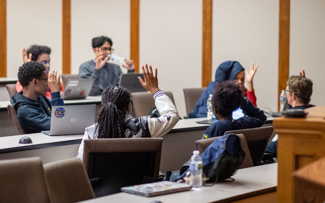 students in classroom raising hands
