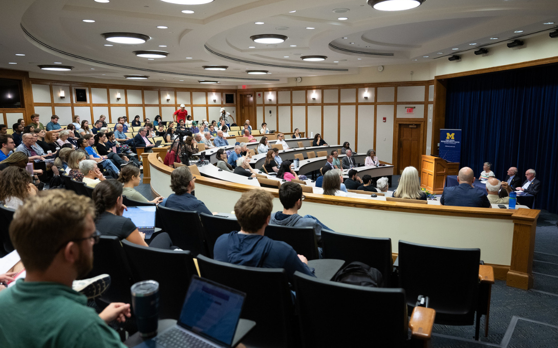 Audience members seated in a lecture hall at the University of Michigan's Ford School, listening to a speaker at the front.