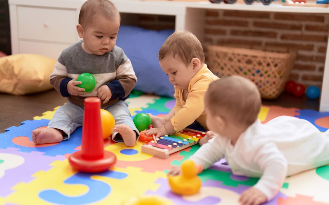 Group of toddlers playing with toys sitting on floor at kindergarten 