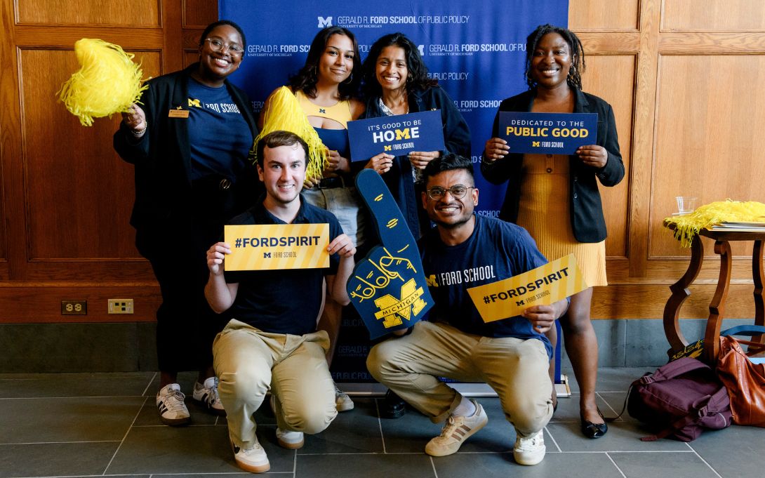 Group of students holding banners and merchandise that read "#FORDSPIRIT" and "Welcome Home" at a Ford School event.
