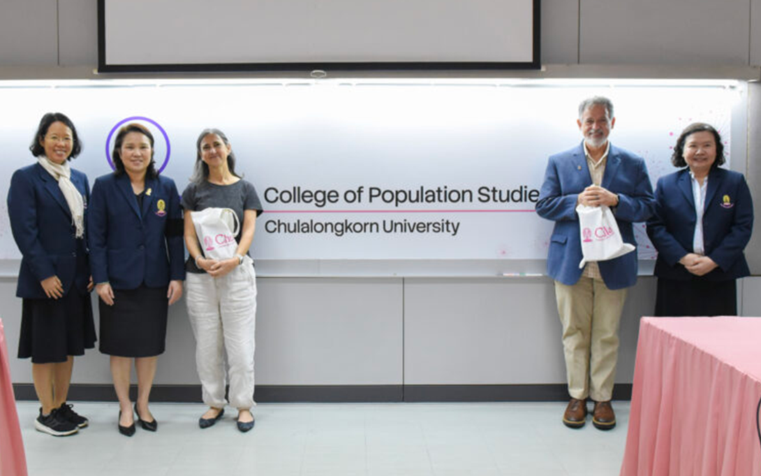 Five individuals standing in front of the "College of Population Studies, Chulalongkorn University" sign, holding promotional bags.