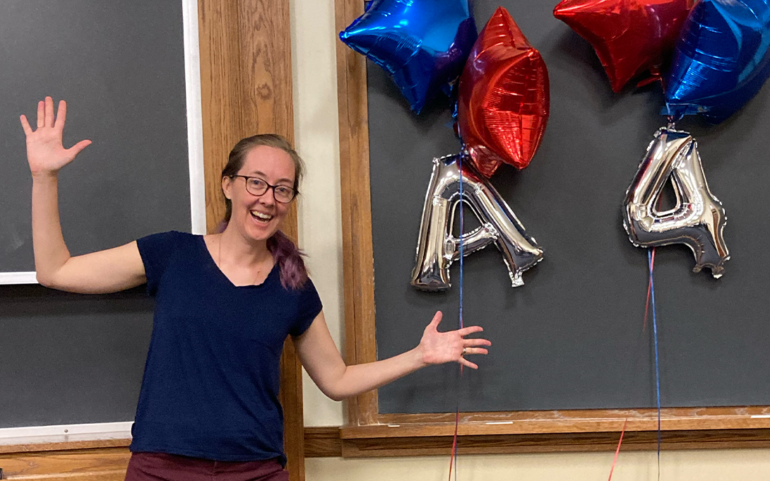 Woman celebrates with balloons in front of a blackboard