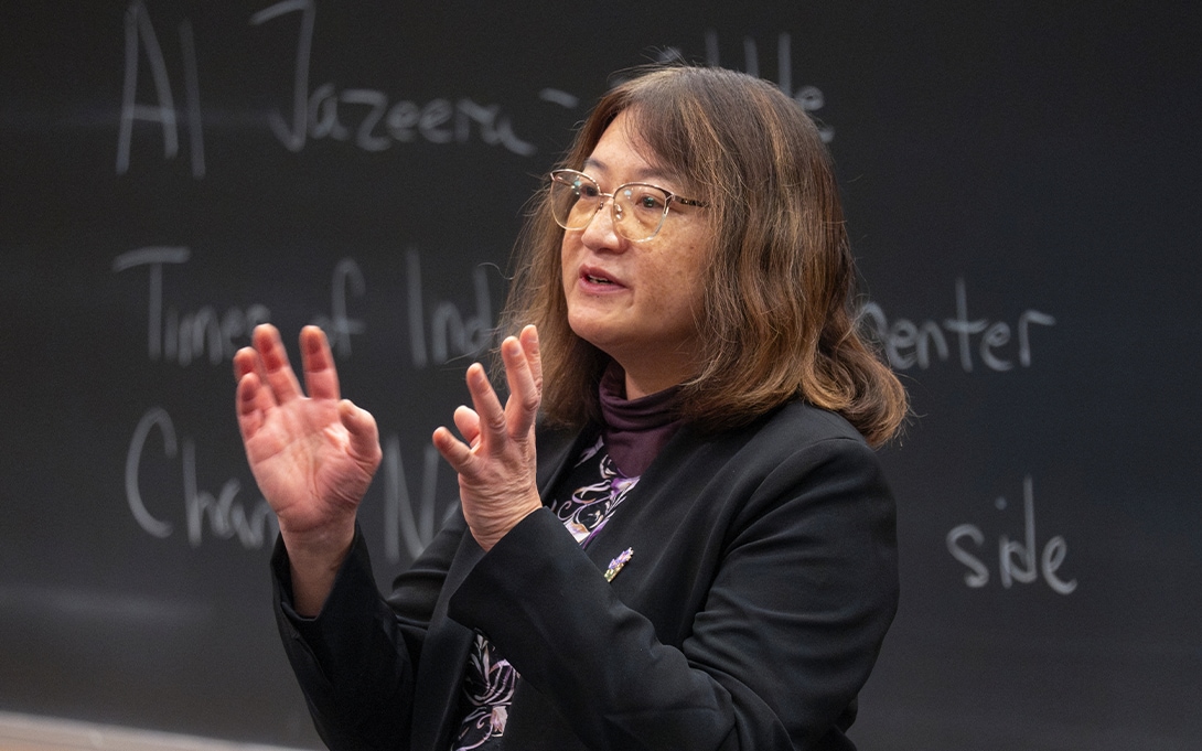 Professor Ann Lin teaching class standing in front of blackboard
