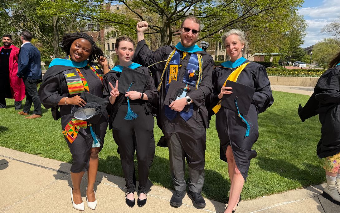 four students celebrating in their graduation robes 