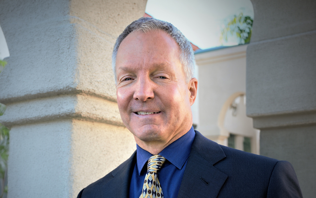 Person in suit and tie smiling standing in front of textured wall