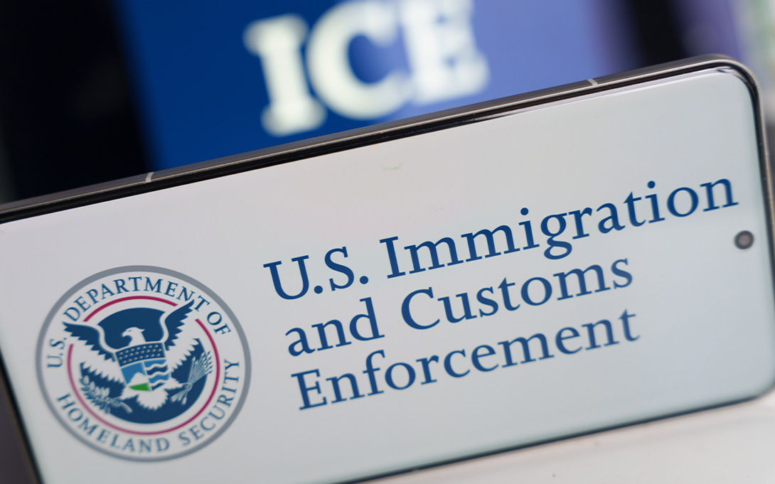 A US Immigration and Customs Enforcement badge with the words 'ICE' in the background