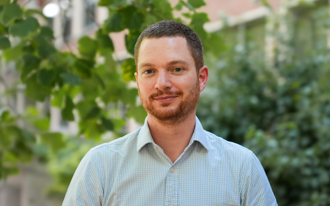 Person smiling with a greenery background