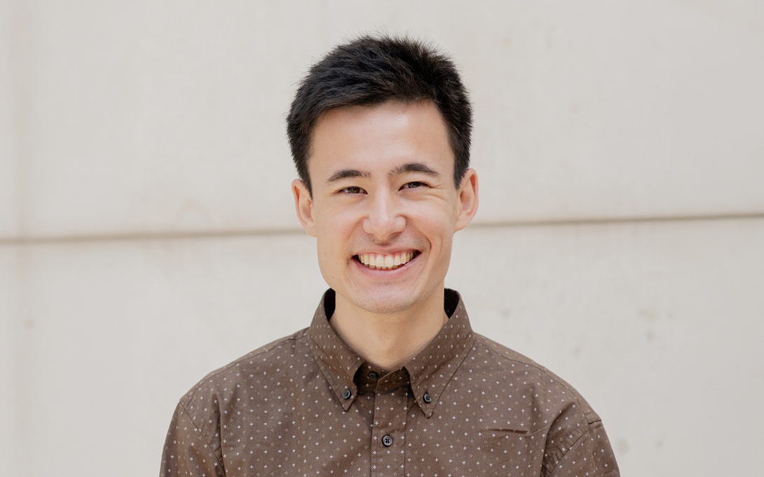 Person smiling against a light wood slat background.