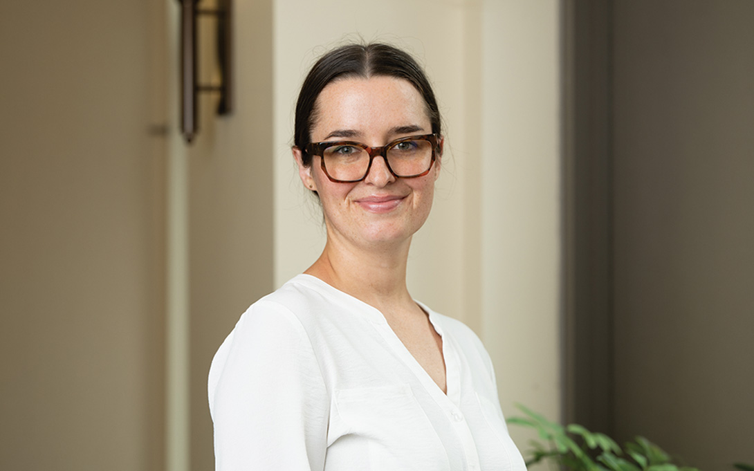 Smiling person in professional dress against a neutral background