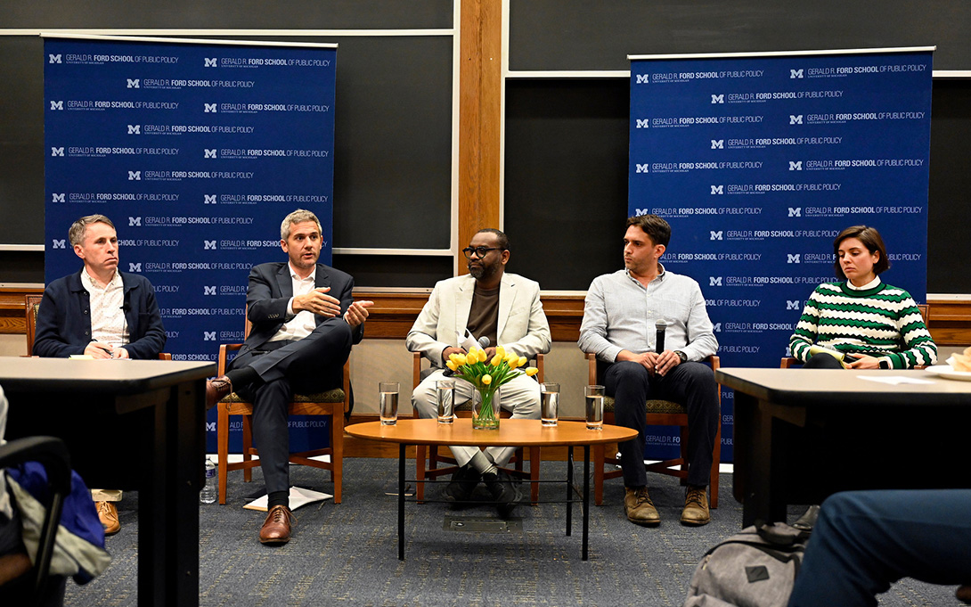 Five panelists sit before Gerald R. Ford School of Public Policy banners as one speaks and gestures to the group.
