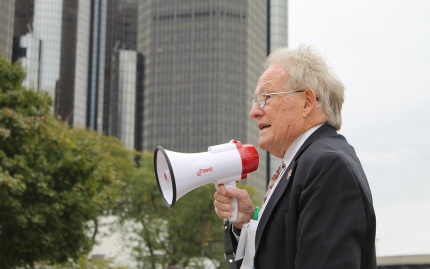 Photo of Ren Farley speaking into a megaphone as he leads a tour of U-M students in downtown Detroit