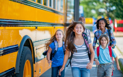 Photo of kids running outside a school bus