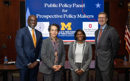 Photo of Hardy Vieux, Maria Cancian, Celeste Watkins-Hayes, and Trevor Brown posed in front of a screen with a slide that says "Public Policy Panel for Prospective Policy Makers"