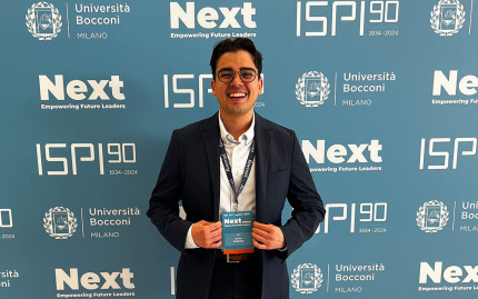 Javi Pinero standing with his conference badge at the NEXT Milan Forum in Italy organized by ISPI, Università Bocconi, and the OECD