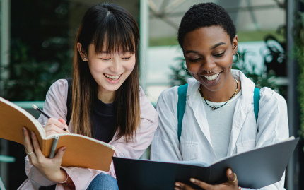 Photo of two students comparing notes, smiling.