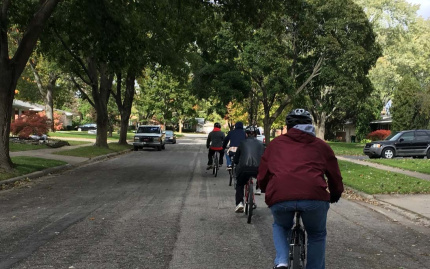 Photo of group riding bicycles down a neighborhood street.