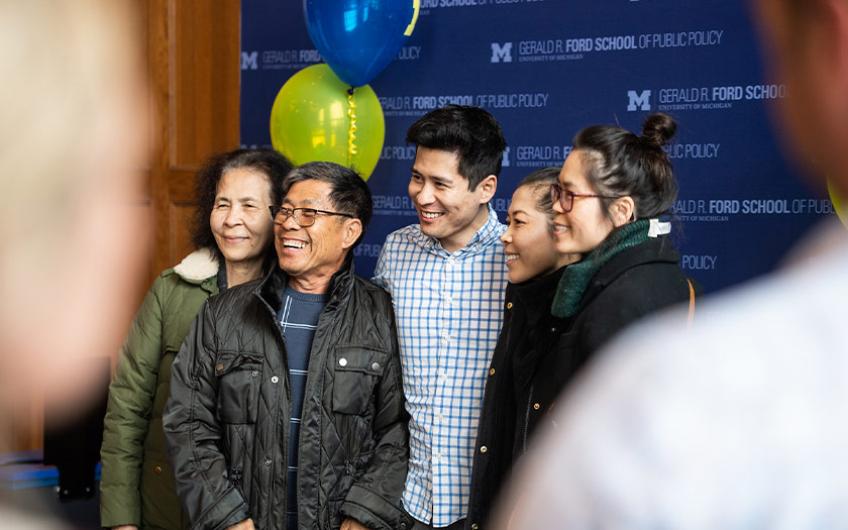 A Ford School graduate and his family celebrating with a photo at the open house photo booth