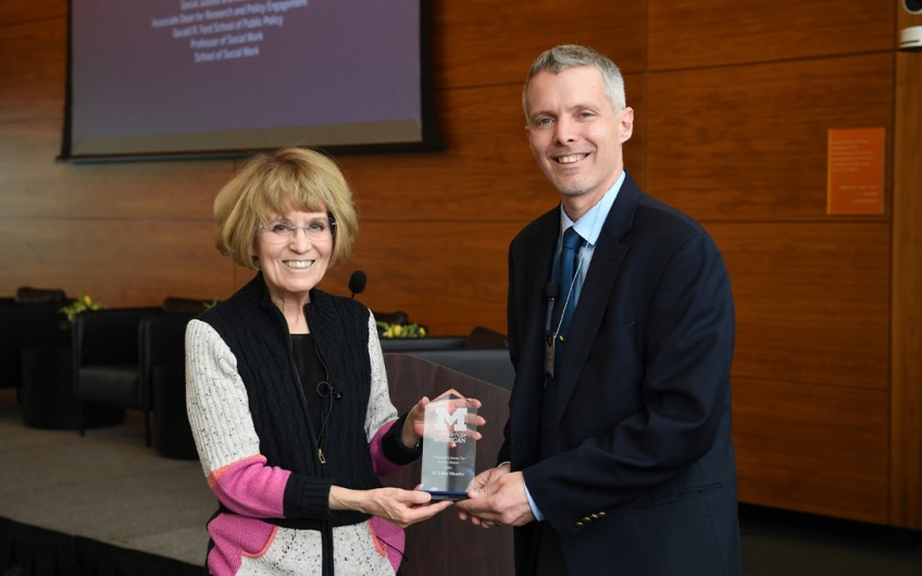 Photo of U-M President Mary Sue Coleman and Professor Luke Shaefer holding the President's Award for Public Engagement