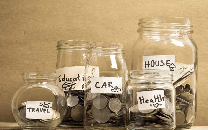 Photo of jars of money, one each labeled for travel, education, car, health, and house.