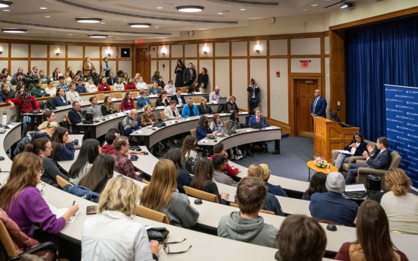 Audience listening to a speaker at a university lecture hall event.