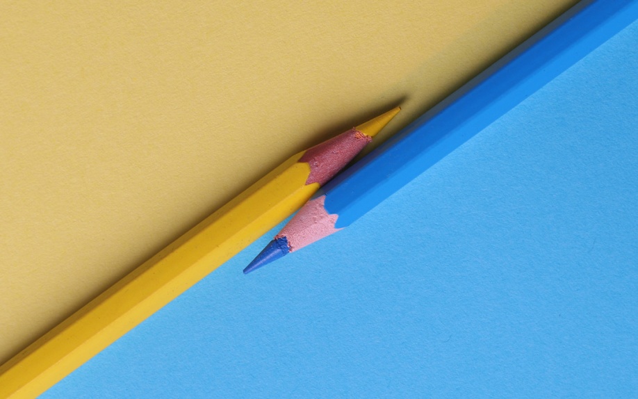 Yellow and blue pencils diagonally bisect a colored background