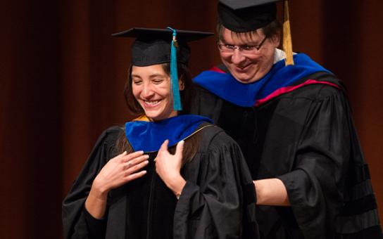 PhD student getting hooded at commencement