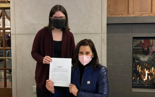Photo of Governor Whitmer and Laura Meyer (MPP '23) with a signed copy of the tampon tax repeal bill