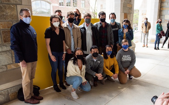 Photo of students and Dean Barr standing in front of a large Block M in the Jeffries Hall Arcade 