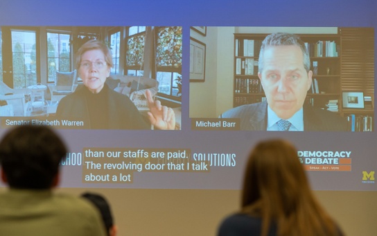 Photo of in-person watch party attendees in Annenberg Auditorium, watching a Policy Talks event with Senator Elizabeth Warren and Dean Michael Barr