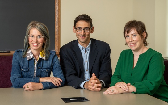 Photo of Molly Spencer, Alex Ralph, and Beth Chimera seated a table in a Ford School conference room