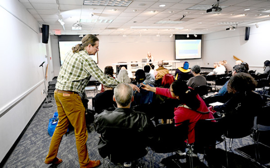 Bechtel offers a microphone to an audience member at a GIG A2 info session