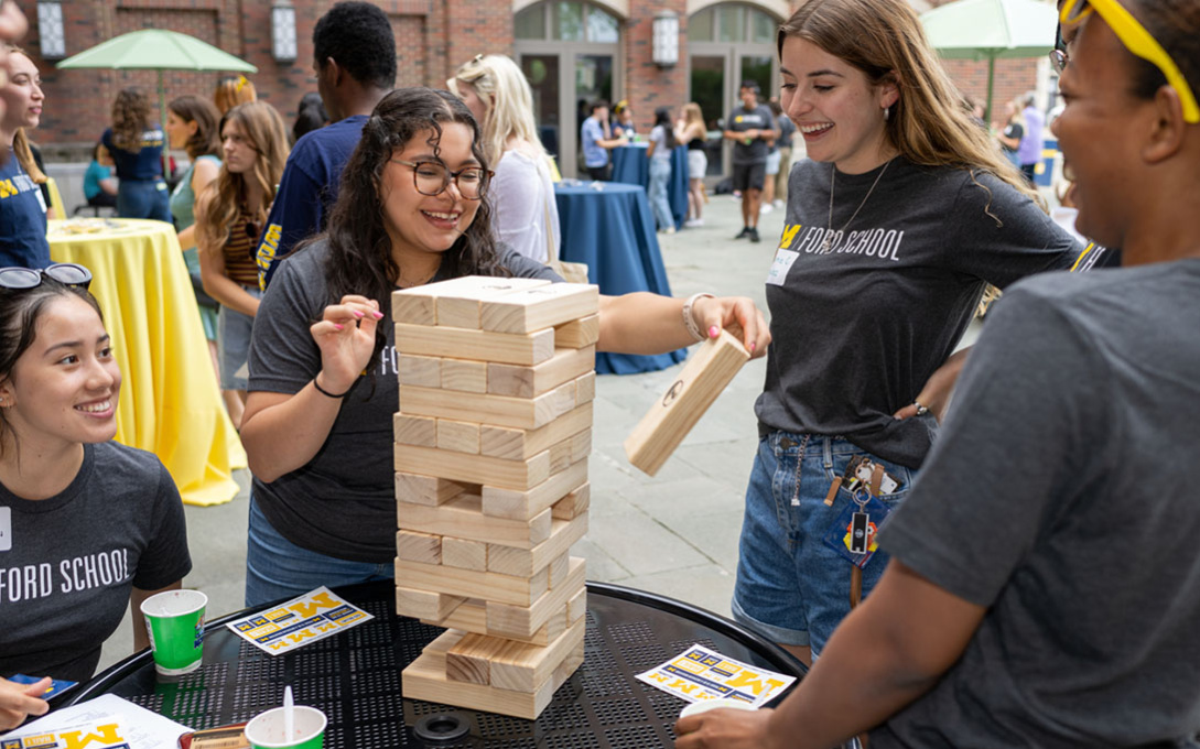 Smiling, PPIA fellows gather around a table while playing Jenga