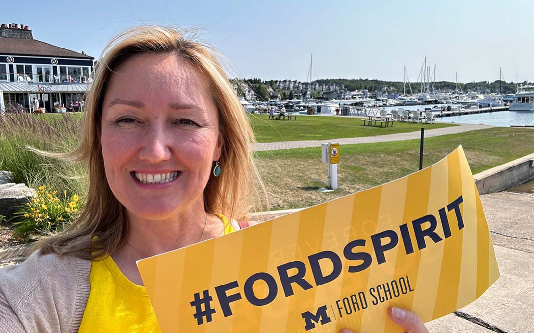 Zuzana Wiseley smiling, holding a maize sign that reads #FORDSPIRIT in Petoskey