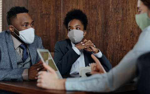 Three people, wearing masks, at a meeting.