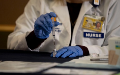 a Michigan Medicine official draws COVID vaccine serum into a needle