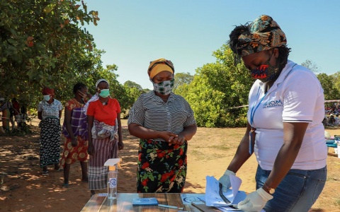 Photo of women in Mozambique, masked and socially distanced, waiting in a queue