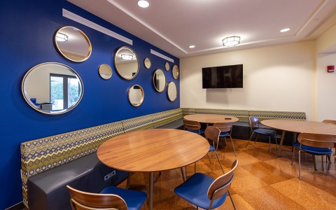 Photo of the Ford School's student lounge, with table and bench seating abutting a blue wall with mirrors.