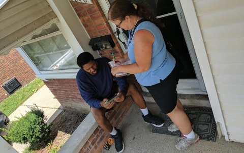 Photo of a DMACS surveyor and a Detroit resident speaking on the front porch of his home
