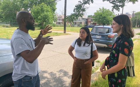 Photo of a community member speaking with two Ford School students on the side of a residential street