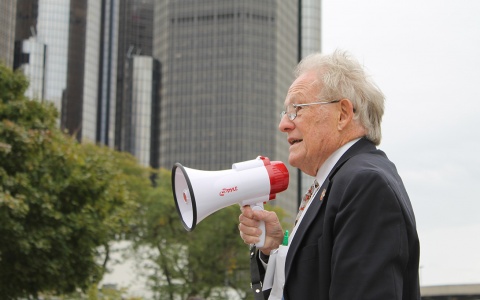 Photo of Ren Farley speaking into a megaphone as he leads a tour of U-M students in downtown Detroit