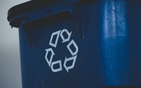Photo of a rolling blue recycling bin featuring the recycling logo in white