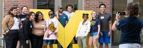 Photo of a group of students in front of a large maize-colored Block M