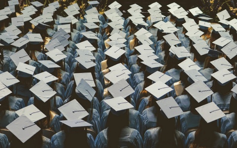 Photo of many rows of soon-to-be graduates seated in an auditorium