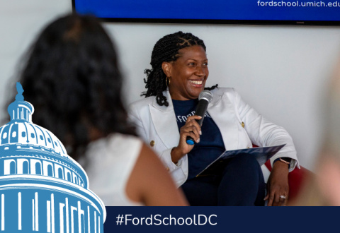 Celeste Watkins-Hayes holding a microphone and smiling. A illustration of the capitol building and the text #FordSchoolDC are below.